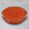 A bowl of tomato soup sits on a marble surface.