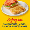 A sandwich with tomatoes and bacon, next to a piece of bread with mustard, promoting the use of the product on sandwiches, meats, salmon and baked hams.