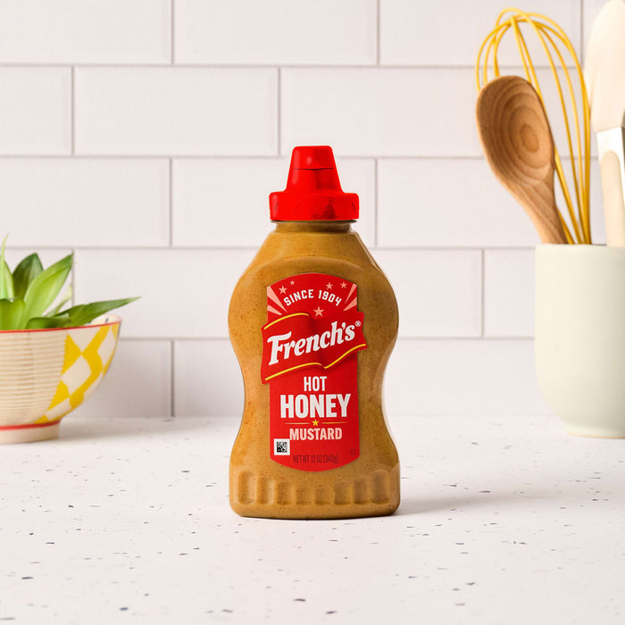 A bottle of Frenches Hot Honey Mustard stands on a white countertop.