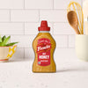 A bottle of Frenches Hot Honey Mustard stands on a white countertop.
