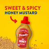 Frank's Sweet &amp; Spicy Honey Mustard bottle on a yellow background with mustard seeds.