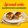 A close-up of two sandwiches on a plate, suggesting the product can be spread onto sandwiches and burgers.