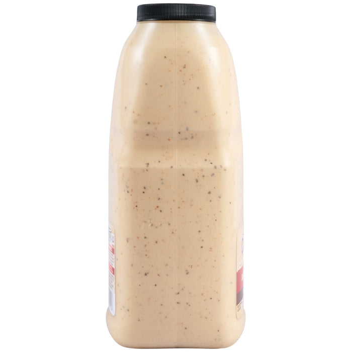 A side profile of a large, clear bottle filled with Cattlemens Alabama White Oz, a creamy white sauce with dark specks.
