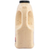A side profile of a large, clear jug of Cattlemens Alabama White Oz, showing the creamy, spice-flecked sauce and the built-in handle.