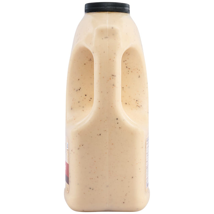 A side profile of a large, clear jug of Cattlemens Alabama White Oz, showing the creamy, spice-flecked sauce and the built-in handle.