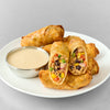 A plate of southwestern egg rolls is served with a side of creamy Cattlemen'S Alabama White Bbq Sauce, 0.5 Gal for dipping.
