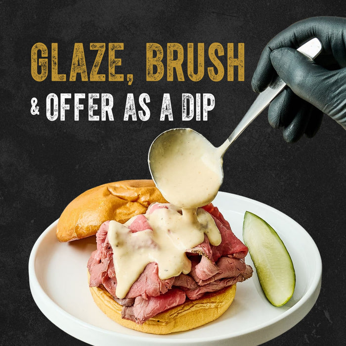 A gloved hand ladles creamy Cattlemen'S Alabama White Bbq Sauce, 0.5 Gal over a roast beef sandwich on a white plate, with the words Glaze, Brush &amp; Dip highlighting the sauce's versatility.