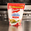 ["A bag of French's Crispy Fried Onions, Original flavor, sits on a stainless steel counter."]