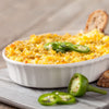 ['A white casserole dish filled with a cheesy dip topped with jalapenos and cilantro.']