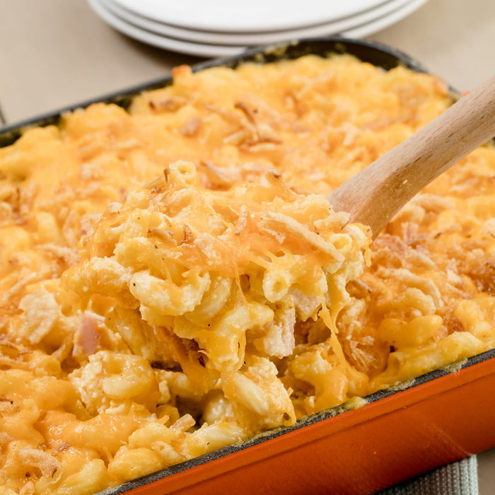 ['A close up of a casserole dish filled with macaroni and cheese topped with crispy fried onions.']