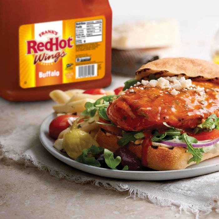 A plate of food with a sandwich topped with Franks RedHot Buffalo Wings sauce.