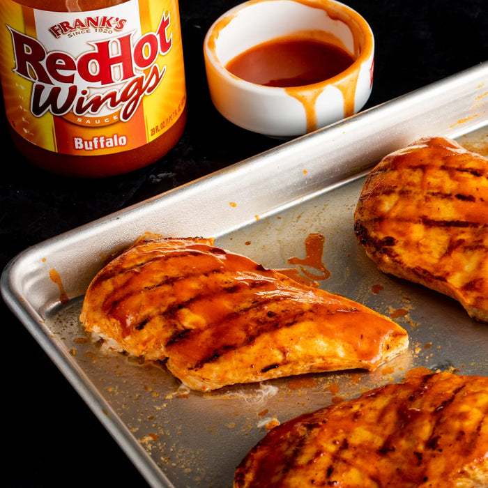A close-up of three grilled chicken breasts covered in Franks RedHot Buffalo Wing Sauce.