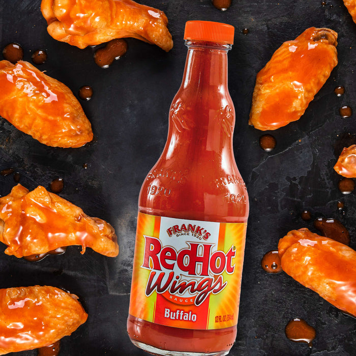 A bottle of Franks RedHot Buffalo Wing Sauce with chicken wings.