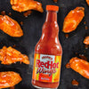A bottle of Franks RedHot Buffalo Wing Sauce with chicken wings.