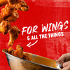 ["Chicken wings are being tossed in a bowl with the text 'For Wings &amp; All The Things' on a red background."]
