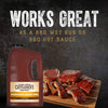 ["A gallon jug of Cattlemen's Mississippi Honey BBQ sauce next to a plate of ribs."]
