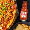 A bowl of buffalo chicken dip with pita chips and a bottle of Frank's RedHot Original Cayenne Pepper Sauce.