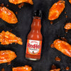 A bottle of Frank's RedHot Original Cayenne Pepper Sauce next to chicken wings.