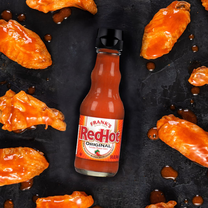 A bottle of Frank's RedHot Original Cayenne Pepper Sauce next to chicken wings.