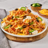 A plate of nachos with chicken, cheese, sour cream, jalapenos, and olives.