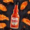A bottle of Frank's RedHot Original Cayenne Pepper Sauce with chicken wings.
