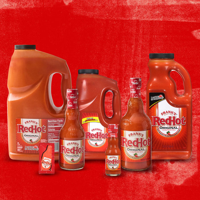 A collection of Franks RedHot bottles of different sizes, including a large jug, a smaller bottle, and a single-serving packet.