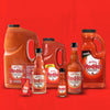 A collection of Frank's RedHot bottles of different sizes, including a large jug, a smaller bottle, and a single-serving packet.