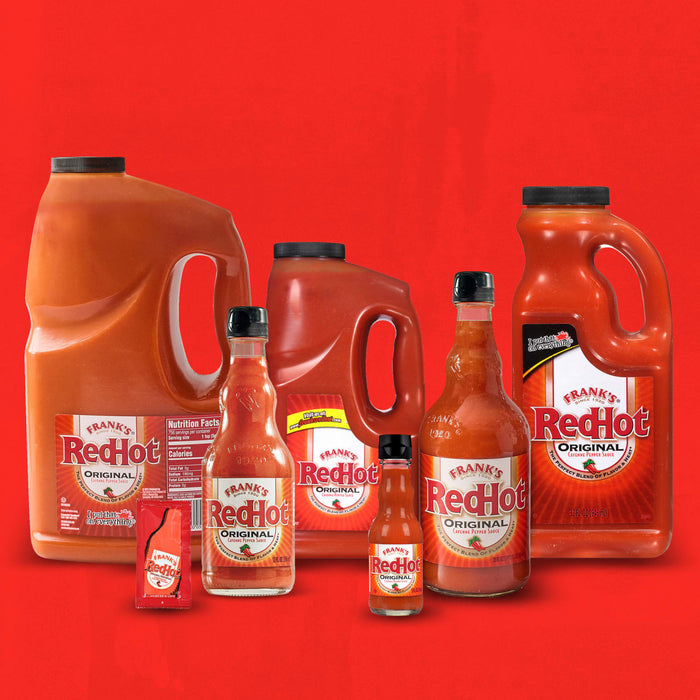 A collection of Frank's RedHot bottles of different sizes, including a large jug, a smaller bottle, and a single-serving packet.