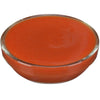 ['A glass bowl filled with a bright orange sauce.']