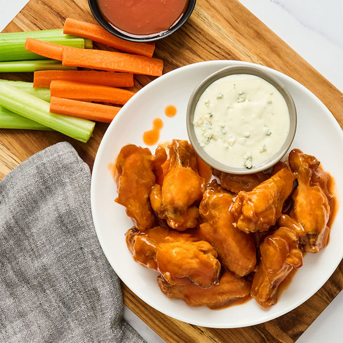 A plate of RedHot Wings with celery sticks and a side of coleslaw.