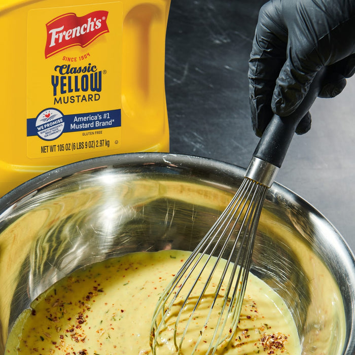 A gloved hand whisks a bowl of Frenchs Classic Yellow Mustard with spices.