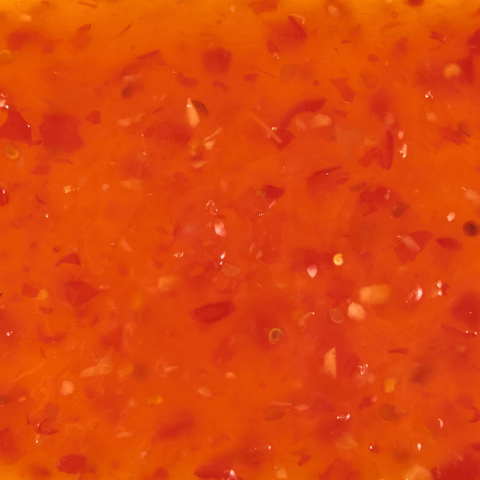 A close-up shot of sweet chili sauce with visible chili flakes and garlic.