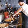 A chef prepares fried rice with a bottle of Frank's RedHot Sweet Chili sauce nearby.