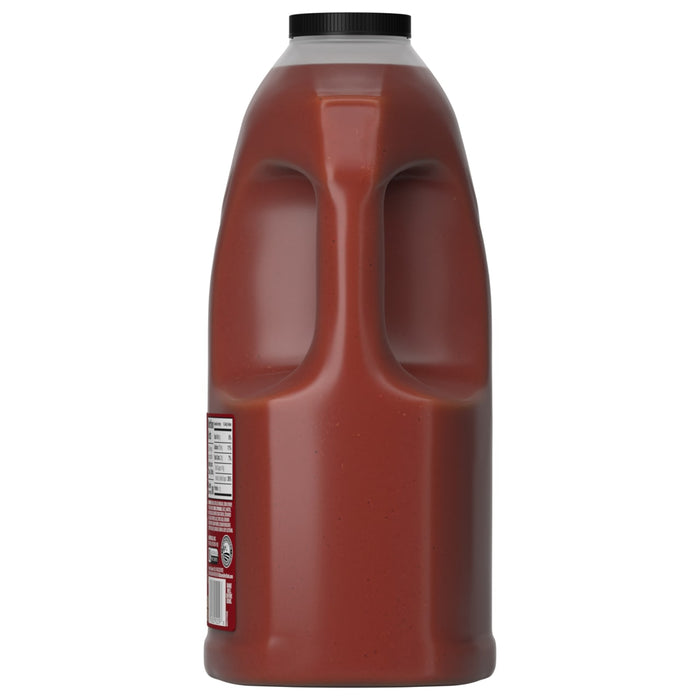 A side view of a large, 128-ounce jug of Franks Red Hot Garlic Regular Hot Sauce Regular 128 Oz, showing the dual-grip handle and nutrition label.