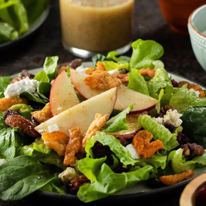 A vibrant autumn salad featuring crisp greens, apple slices, and candied pecans is ready to be tossed with a dressing made from Frenchs Beige Stone Ground Dijon Mustard 12 Oz.
