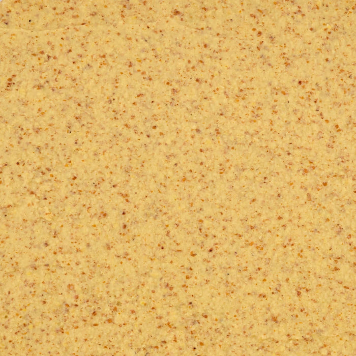 A close up overhead view shows the thick and grainy texture of Frenchs Beige Stone Ground Dijon Mustard 12 Oz with visible brown mustard seeds throughout.