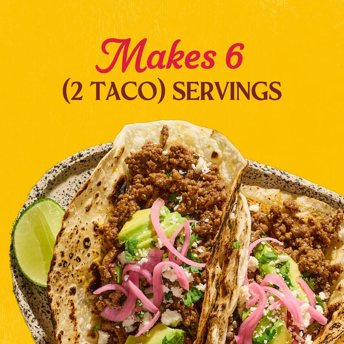 A close up view of two street tacos topped with ground meat, avocado, and pickled onions to show that the Cholula Medium Taco Seasoning Mix 1 Oz makes six servings of two tacos each.
