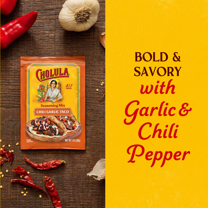 A package of Cholula Medium Chili Garlic Taco Seasoning Mix 1 Oz is displayed on a rustic wooden surface surrounded by fresh garlic cloves and dried red chili peppers against a bold yellow background with descriptive text.