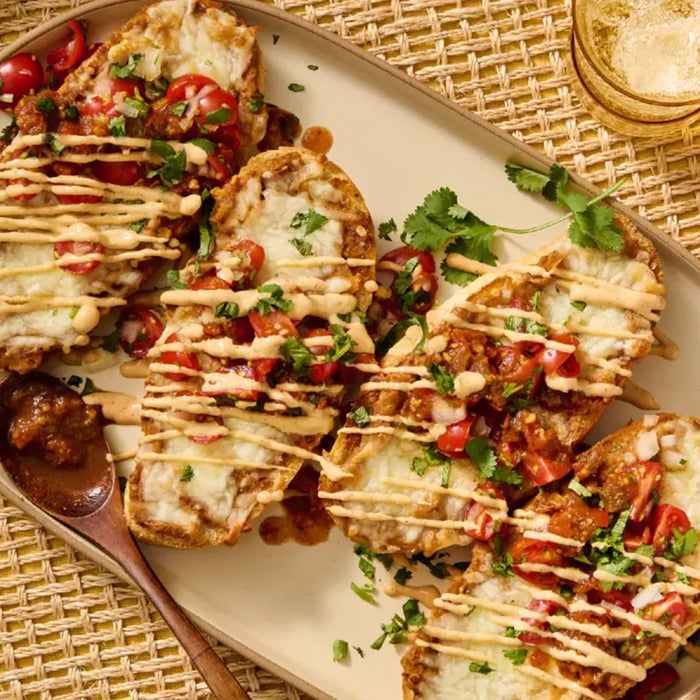 A platter of toasted molletes topped with melted cheese and a fresh pico de gallo salsa made using Cholula Medium Chili Garlic Taco Seasoning Mix 1 Oz.