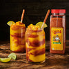 Two glasses of mango margarita with chili lime seasoning and a bottle of Cholula Chili Lime seasoning.