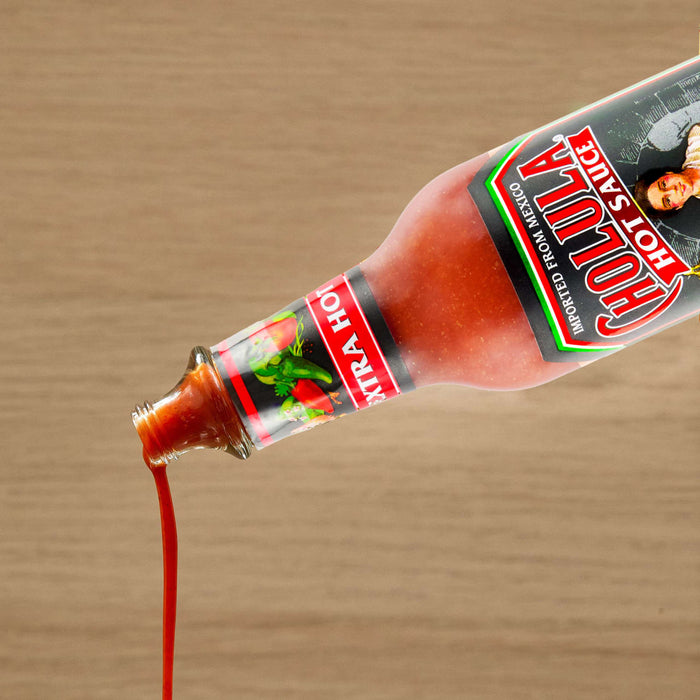 A bottle of Cholula Hot Sauce is pouring out its contents.