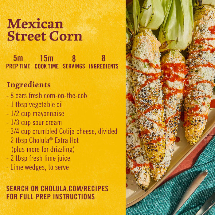 A plate of Mexican street corn with Cholula hot sauce, cotija cheese, and lime wedges.
