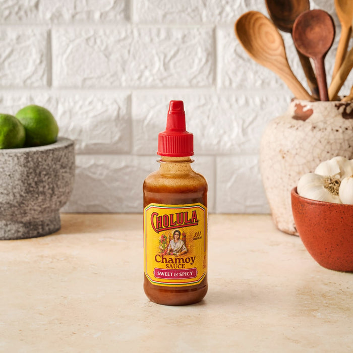 A bottle of Cholula Chamoy Sweet &amp; Spicy sauce sits on a kitchen counter.