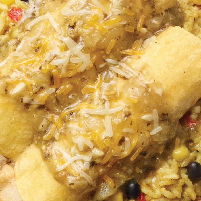 A close-up shot of a plate of food featuring rice, black beans, corn, and topped with what appears to be fried plantains covered in cheese and sauce.