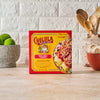 A box of Cholula Fiesta Ranch Dip Mix sits on a counter next to limes and kitchen utensils.