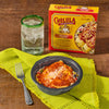 A Cholula-branded meal kit is displayed with a prepared serving a drink and a fork suggesting a convenient and flavorful dining experience.