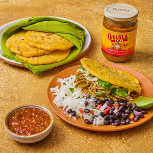 A plate of food featuring Cholula Original Hot Salsa, pupusas, rice, and black beans.