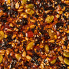 A close-up shot reveals a dense mixture of seeds nuts and dried fruits bound together by a glossy dark syrup creating a visually appealing and textured food composition.