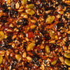 A close-up shot reveals a dense mixture of seeds nuts and dried fruits bound together by a glossy dark syrup creating a visually appealing and textured food composition.