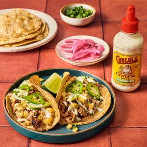 A plate of tacos with Cholula Cremosa Cilantro Lime sauce pickled onions and cilantro.